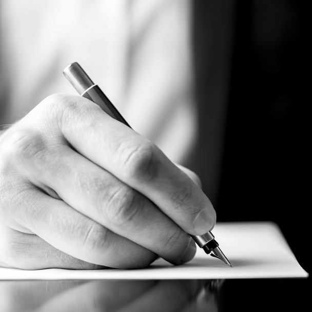 mannelijke hand met een vulpen alsof schrijven - Foto, afbeelding