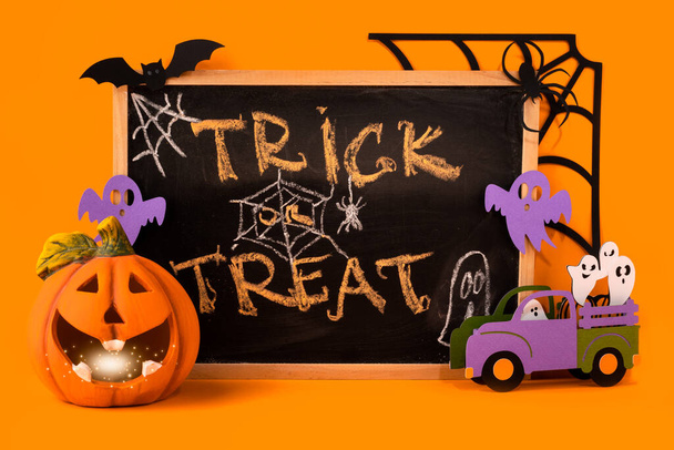 Boldog halloween ünnep koncepciót. Jack o lámpa, kézzel készített papír dekoráció, szellemek, denevér, pók, web, trükk vagy kezelésére szöveg kréta keret narancs alapon. Halloween fesztivál, üdvözlőlap. - Fotó, kép