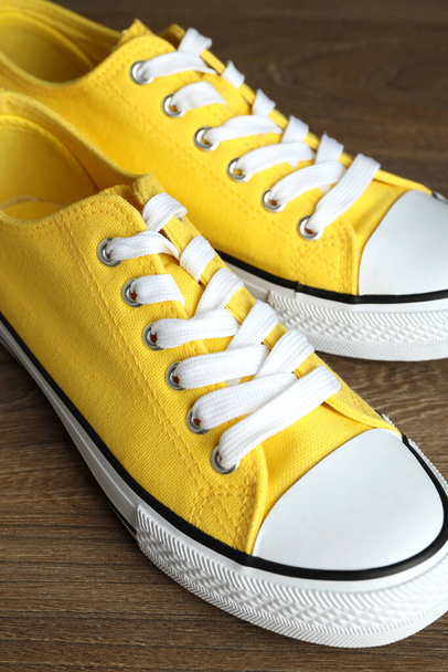 Пара желтых кроссовок на деревянном фоне - Фото, изображение