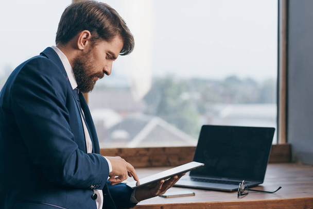 férfi öltönyben közel az ablakhoz egy laptop kommunikáció - Fotó, kép