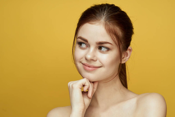 pretty woman naked shoulders and posing clear skin yellow background - Fotó, kép