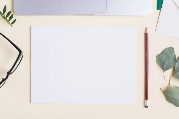 blank white paper pencil eyeglasses leaves laptop beige backdrop. High quality photo - Photo, Image