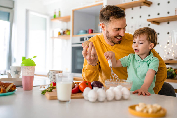 Happy family home fun kitchen concept. Smiling father with children preparing healthy food and spending time together - Foto, afbeelding