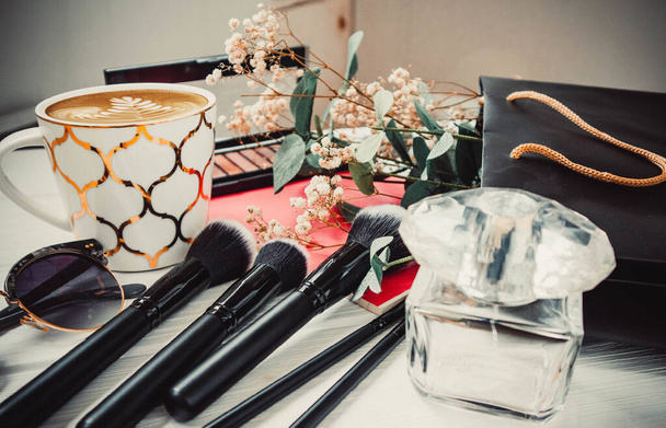 Tasse Kaffee, Lidschattenpalette und Gläser auf weißem Holzhintergrund im Sommer - Foto, Bild