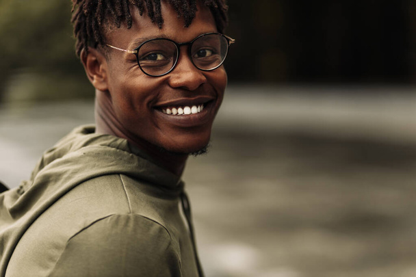Happy african american man, wearing glasses looking at camera, cheerful black man posing outdoors in city - Φωτογραφία, εικόνα