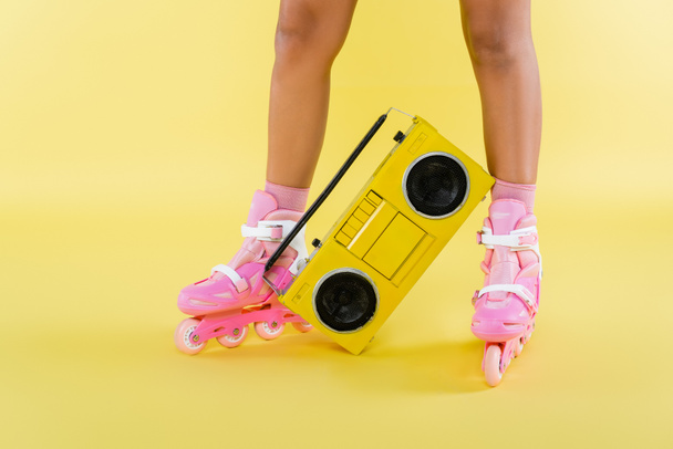 cropped view of african american woman in roller skates near retro boombox on yellow - Foto, imagen