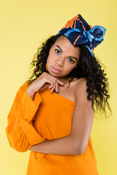 curly african american woman in headscarf and bare shoulder posing isolated on yellow - Fotoğraf, Görsel
