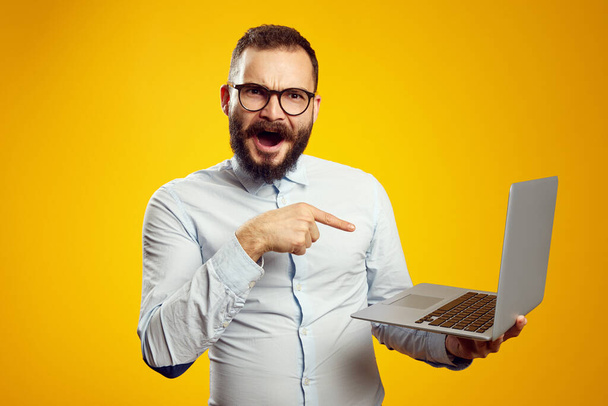 Man wearing eyeglasses screaming with excitement and pointing at new laptop - Fotoğraf, Görsel