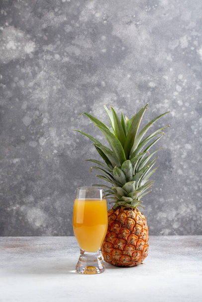 Pineapples and glass of pineapple juice on gray background. Copy space. - Photo, Image