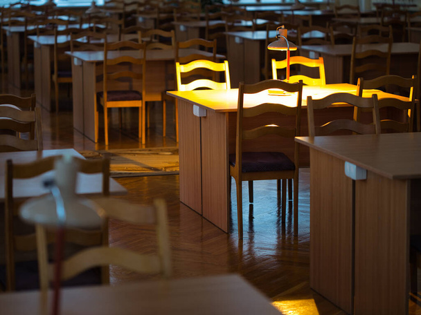 ήσυχη ήρεμη ατμόσφαιρα στη βιβλιοθήκη αμυδρό φως προσωπική λάμπα 2021 - Φωτογραφία, εικόνα