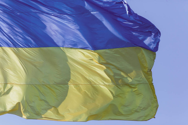 De gele en blauwe vlag van Oekraïne op de vlaggenmast wappert in de wind - Foto, afbeelding