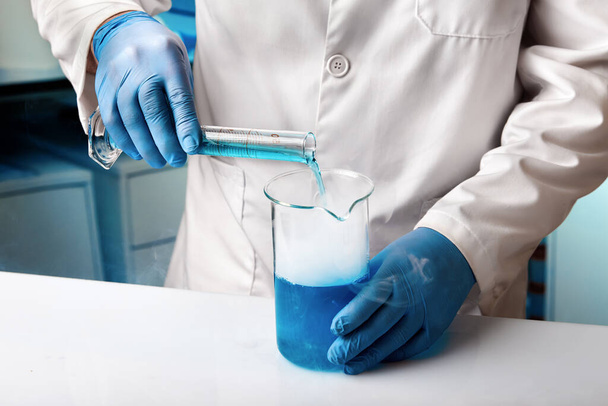 Badacz w laboratorium badawczym pracującym nad opracowaniem eksperymentów z płynami. Naukowiec pracujący z rurkami do mieszania płynów w laboratorium chemicznym - Zdjęcie, obraz