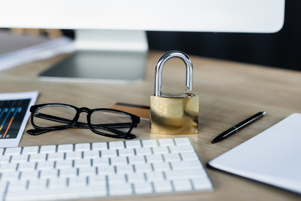 Padlock near eyeglasses and computer on table in office  - Photo, Image
