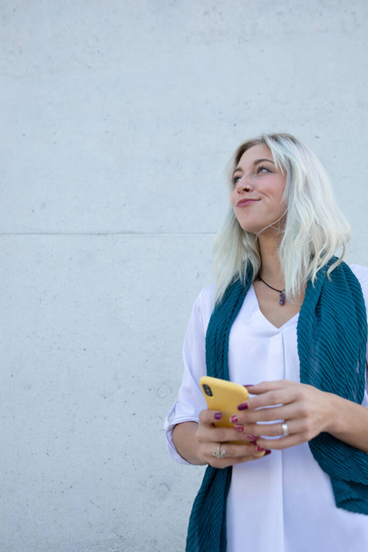 eine elegante und selbstbewusste junge professionelle blonde Frau mit einem Smartphone - Foto, Bild