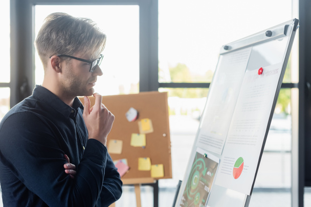 Side view of pensive developer looking at flip chart in office  - Photo, Image