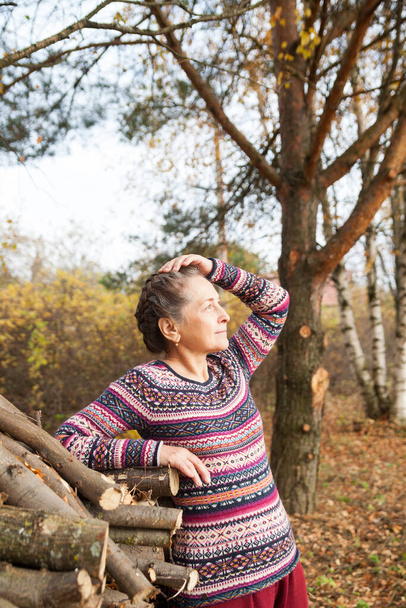 Retrato de una mujer muy anciana en suéter sobre el fondo del paisaje otoñal. - Foto, imagen