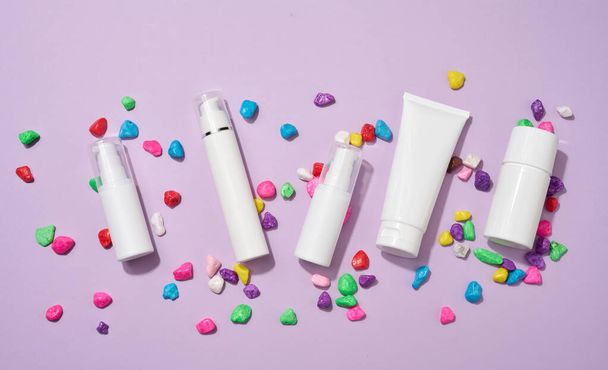 frasco, botella y tubos de plástico blanco vacío para cosméticos sobre un fondo púrpura. Embalaje para crema, gel, suero, publicidad y promoción de productos, maqueta - Foto, imagen