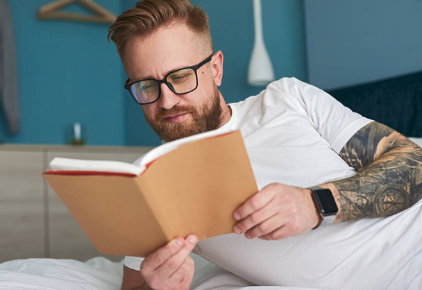 Man reading book on bed - Photo, Image