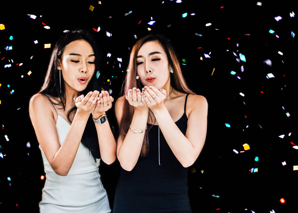 2人のアジアの若い女性のお祝いパーティーグループは、コンフェッティ幸せと面白い概念を保持します。正月に. - 写真・画像