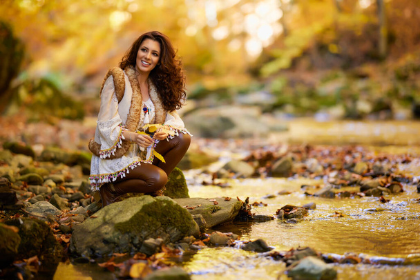 Autumn portrait with a beautiful woman in different positions near a mountain river in the autumn season. - Valokuva, kuva