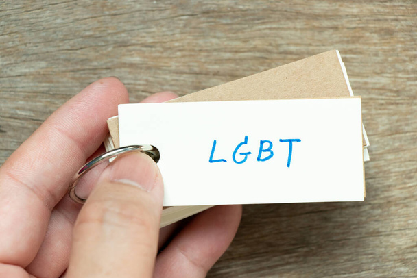 Uomo in possesso della scheda flash con la parola di scrittura a mano LGBT (Abbreviazione di lesbiche, gay, bisessuali e transgender) su sfondo di legno - Foto, immagini