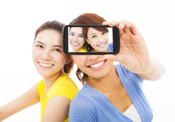 zwei glückliche junge Mädchen machen ein Selfie vor weißem Hintergrund - Foto, Bild