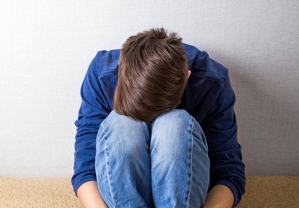 Sad Young Man on the Couch by the Wall - Photo, Image