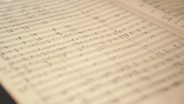 Rayo de luz pasa página amarillenta de cuaderno musical en formato álbum con filas y columnas de notas escaneando información macro - Metraje, vídeo