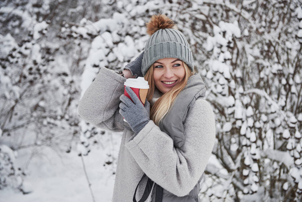Happy young woman. Portrait of cute blonde in warm clothes that enjoying spending her weekend outdoors in the winter forest. - Foto, Bild