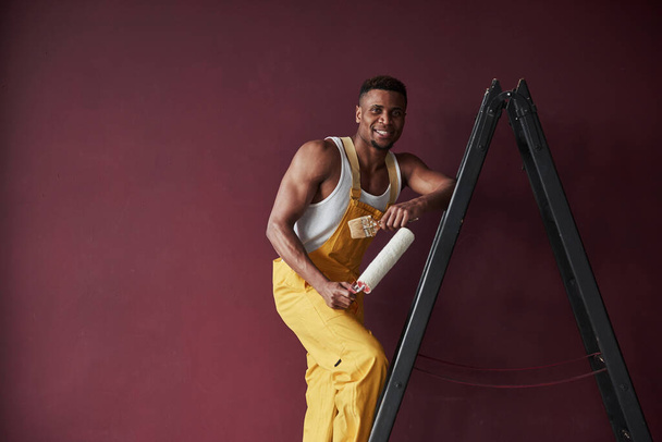 Happy man. Young african american worker in the yellow uniform have some job. - 写真・画像