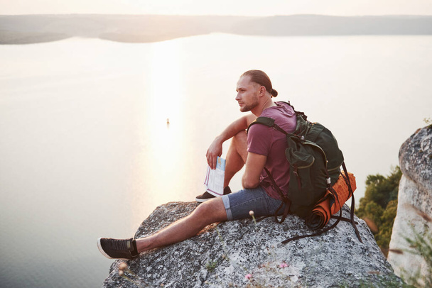 Attractive man with map enjoying the view of the mountains landscape above the water surface. Travel Lifestyle adventure vacations concept. - Valokuva, kuva