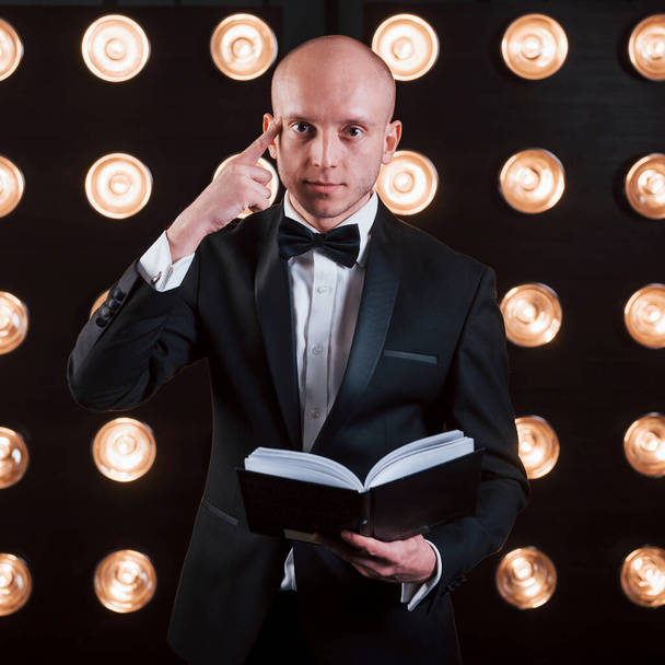 Reading your mind. Magician in black suit standing in the room with special lighting at backstage. - Fotoğraf, Görsel
