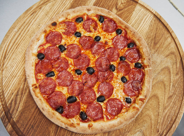Top view. Picture of prepared delicious pizza with sausage rings and olives. - Foto, afbeelding