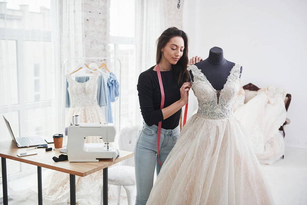 Imagines how it will sit on the bride. Female fashion designer works on the new clothes in the workshop. - Foto, Imagen