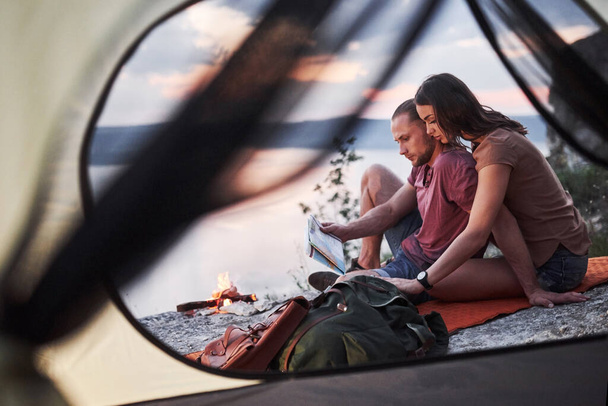 View from tent of couple with map lying a view of lake during hiking trip. avel Lifestyle concept adventure vacations outdoor. - 写真・画像