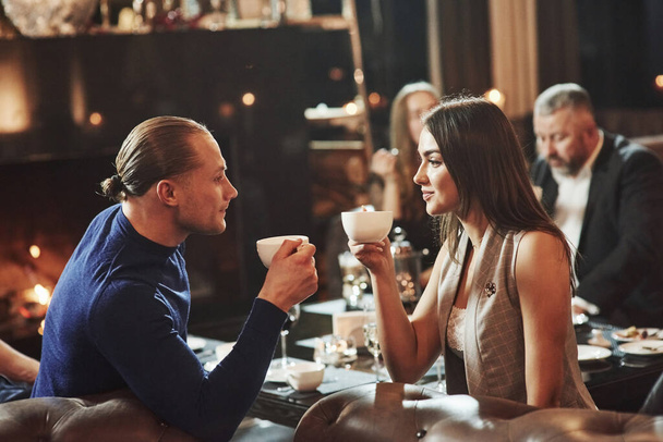 Drinking tea and looking at each other. Beautiful couple. Family friends having nice time in beautiful luxury modern restaurant. - Zdjęcie, obraz