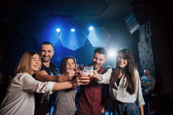 We have all weekends. Group of young friends smiling and making a toast in the nightclub. - Foto, afbeelding