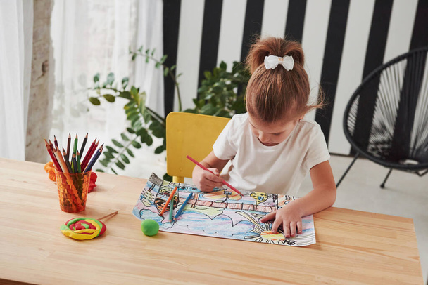 Concentrated at work. Cute little girl in art school draws her first paintings by pencils and markers. - 写真・画像