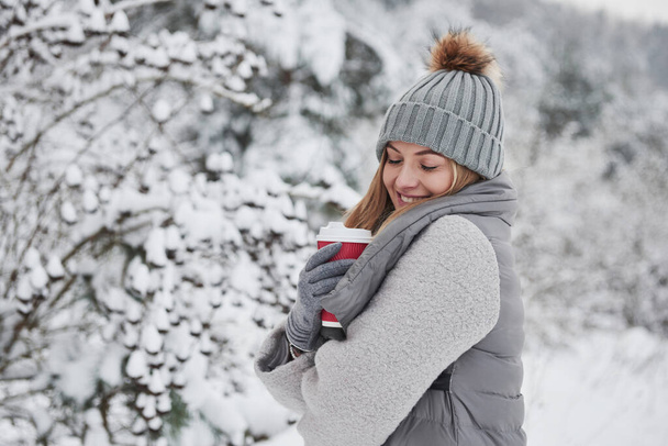 Boldog havas napot. Portré aranyos szőke meleg ruhákban, hogy élvezi tölteni a hétvégét a szabadban a téli erdőben. - Fotó, kép