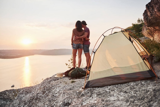 Photo of happy near tent with a view of lake during hiking trip. Travel Lifestyle adventure vacations concept. - 写真・画像