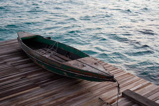 Oude houten boot zittend op de pier met uitzicht op de prachtige Semporna turquoise zee. - Foto, afbeelding