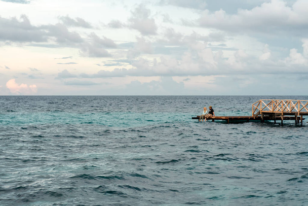 Semporna, Malajsie - 25. listopadu 2019: Dřevěný prázdný dok na terase nebo molo. Dřevěné molo molo modré moře & nebe pozadí. Pohled na dřevěný dok v modrém moři. Perspektiva starého dřevěného mola na pobřeží s jasně modrou oblohou a tyrkysovým mořem nebo mořskou vodou - Fotografie, Obrázek
