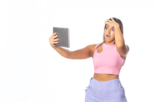 mujer joven y atractiva empresaria mirando el mvil y consultando la tablet, expresión de alegra y enfado - Foto, Imagen