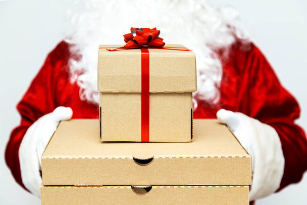 Pizza boxes and a gift in the hands of Santa Claus.  Christmas fast food delivery.  New year's eve promotion. - Foto, Bild