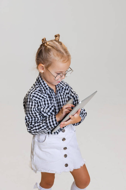 Cropped muotokuva pikkutyttö, lapsi kirjoittamalla tabletin eristetty harmaalla pohjalla - Valokuva, kuva