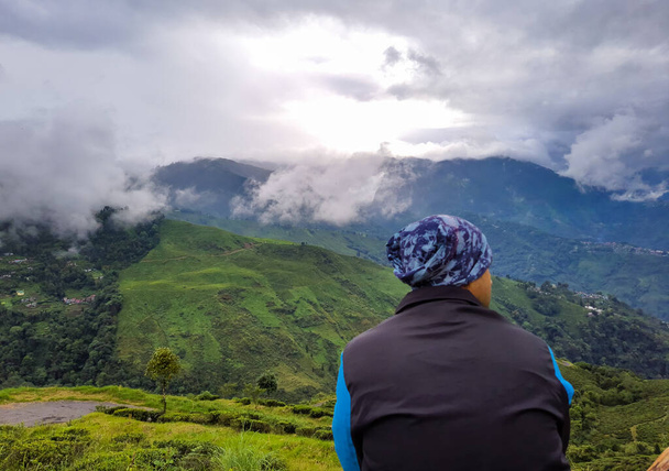 Sabah dramatik gökyüzü ile dağın tepesinde oturan adam Darjeeling Batı Bengal Hindistan 'da görüntülenir.. - Fotoğraf, Görsel