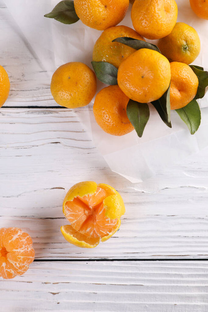Pequeñas mandarinas con hojas sobre un fondo de madera blanca - Foto, Imagen