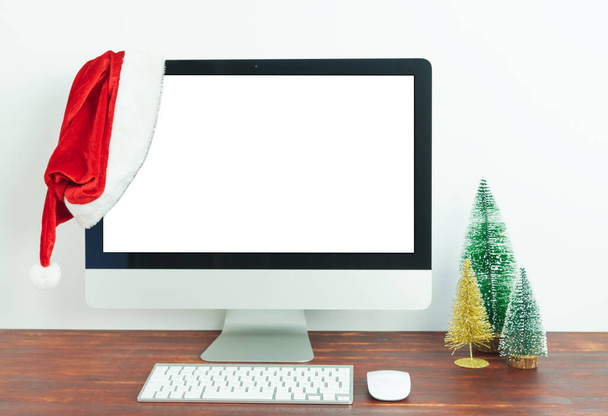 Ordenador con pantalla blanca en escritorio de madera con decoración navideña. Burla. - Foto, Imagen