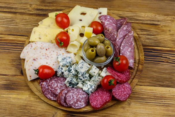 Antipasti platter with olives, cherry tomatoes, assortment of italian salami and cheese on a wooden table. Top view - Photo, Image