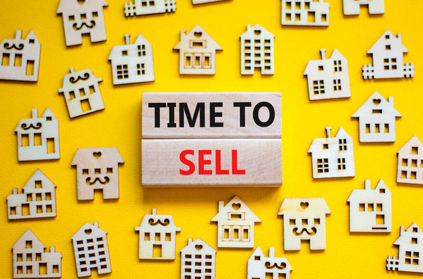 Time to sell house symbol. Concept words 'Time to sell' on wooden blocks near miniature houses. Beautiful yellow background, copy space. Business and time to sell house concept. - Fotoğraf, Görsel